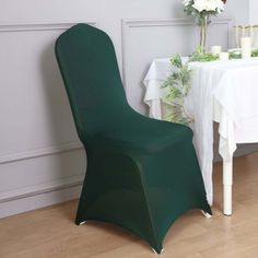 a green chair next to a white table with flowers on it and candles in the background