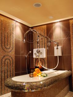 a bathtub in the middle of a tiled bathroom with shower head and hand held faucet