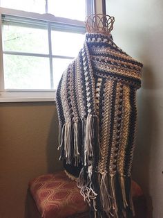 a crocheted shawl hanging from a window sill next to a chair