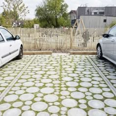 two cars parked in front of a fence with grass growing on the ground next to them