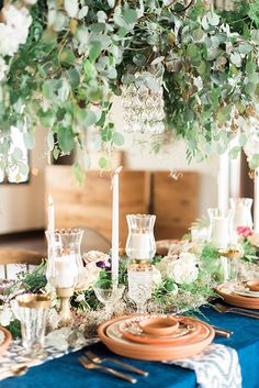 the table is set with candles, plates and napkins for an elegant dinner party