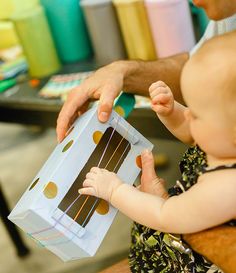 a man holding a baby in front of a box with chocolates on it's wrapper