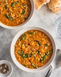 two bowls of soup with bread on the side