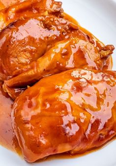 two pieces of chicken covered in sauce on a white plate