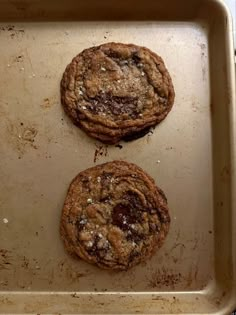 two chocolate chip cookies sitting on top of a pan