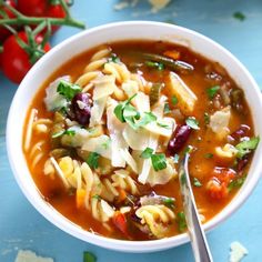 a white bowl filled with pasta soup and garnished with parmesan cheese