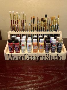 a wooden tray holding many different types of paint and brushes on it's side