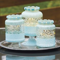 four glass jars sitting on top of a metal tray