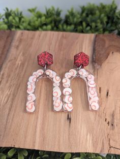 two candy canes are sitting on top of a piece of wood with red and white beads