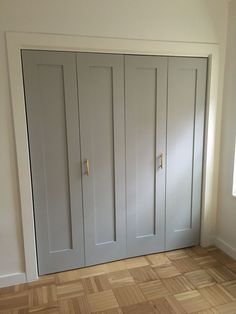 an empty room with white doors and wood flooring on the side of the wall