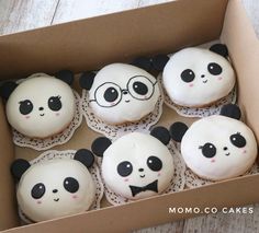 a box filled with lots of cupcakes covered in white frosting and panda faces