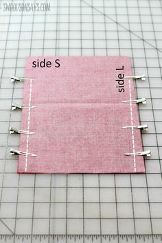 a piece of fabric with pins attached to it on top of a cutting mat and ruler