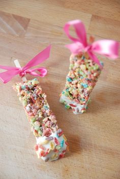 two candy bars with sprinkles and pink bows on them sitting on a table