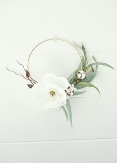 a white flower and greenery wreath on a wall