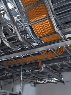 an overhead view of pipes and wires in a building with orange paint on the ceiling