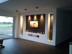 an empty living room with sliding glass doors leading to a patio area and large screen tv on the wall