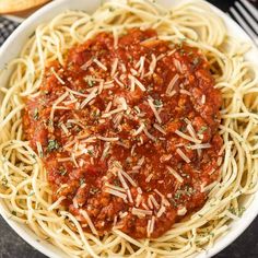 a white bowl filled with spaghetti sauce and parmesan cheese on top of it