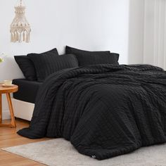 a bed with black comforter and pillows in a room