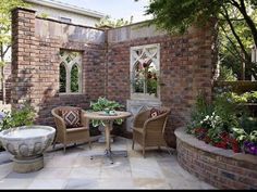 two wicker chairs sitting on top of a patio next to a table and potted plants