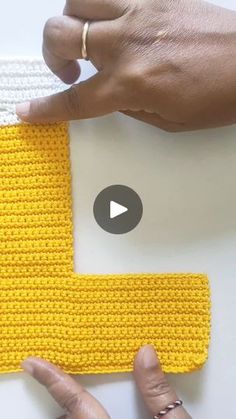 someone is crocheting the letters on a piece of knitted material with their thumbnails