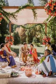 a group of people sitting around a table with food and drinks on top of it