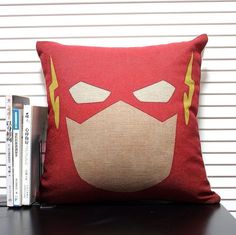 a pillow with the flash symbol on it sitting next to a stack of books and dvds