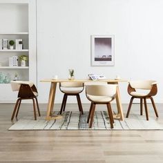 a dining table with four chairs and a rug on the floor in front of it