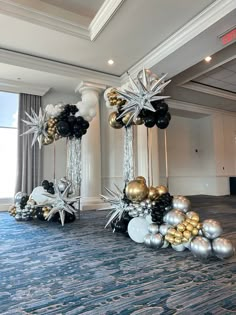 two tall silver and gold balloons in the middle of a room