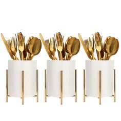 four white cups with gold forks and spoons in them, all lined up against each other