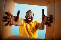 a man in a cardboard box making the middle finger sign with his hands as if to say something