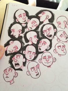 a person holding up a book with many faces drawn on it