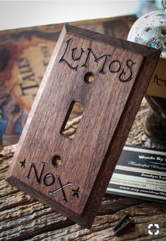 a wooden light switch cover with the words lumos and nox written on it