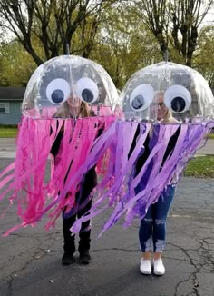 two girls are holding up jellyfish balloons with googly eyes and purple streamers