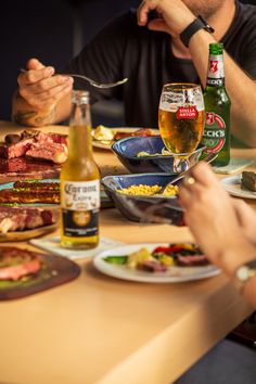 several people sitting at a table eating food and drinking beer