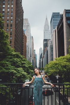 a woman standing in the middle of a city with her arms outstretched and looking up