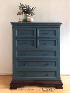 a blue dresser with flowers on top and a potted plant sitting on top of it