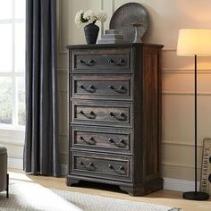 an old chest of drawers in a living room with a lamp on the side table