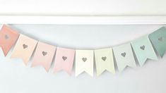 a paper banner with hearts hanging from it's sides in pastel colors on a white wall