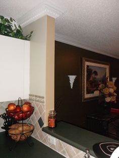 a bowl of fruit sitting on top of a kitchen counter next to a potted plant