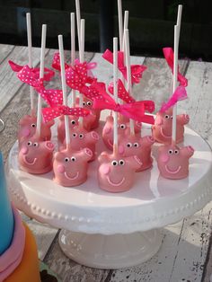 there are many pink pigs on the cake plate with toothpicks in it's mouth