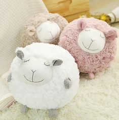 two stuffed sheep sitting next to each other on a white rug with an open book