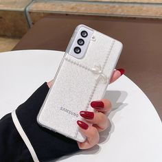 a woman's hand holding a clear samsung phone case with bows on the front