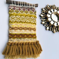 a piece of cloth next to a mirror on a white surface with a gold brooch