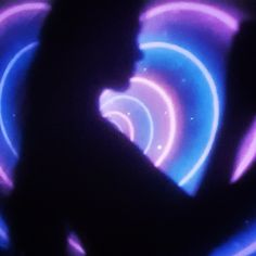 the silhouette of a person using a cell phone in front of an abstract light painting