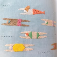 a close up of an embroidered object on a blue cloth with different shapes and sizes