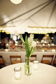 two vases filled with flowers sitting on top of a white tablecloth covered table