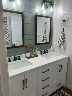 a bathroom with two sinks, mirrors and lights on the wall above them is decorated in black and white