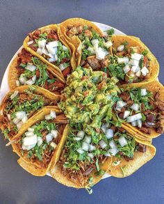 an overhead view of tacos with toppings on a white platter against a blue background