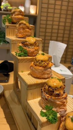 several stacks of food sitting on top of wooden boxes with parsley and cheese toppings