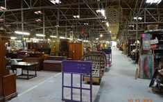 a warehouse filled with lots of furniture and wooden pieces of furniture in it's center aisle